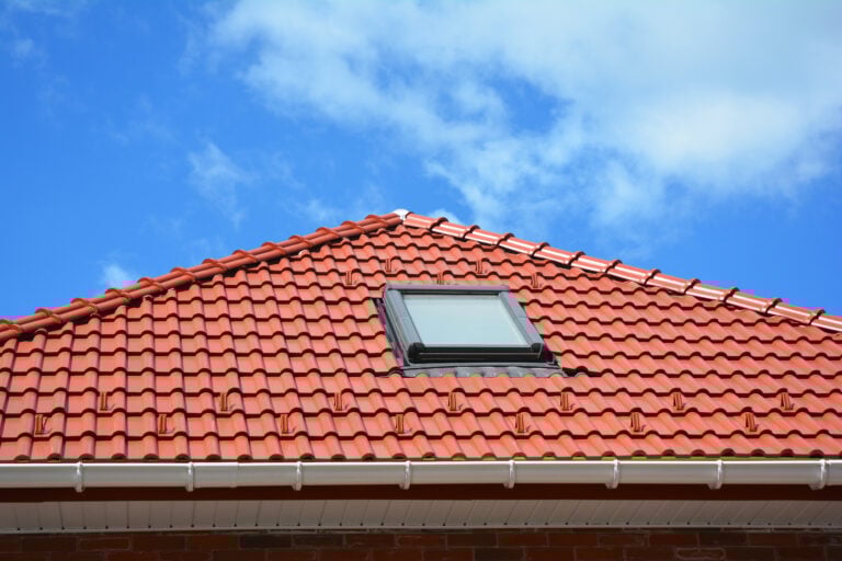 Skylight on red ceramic tiles house roof with rain gutter.