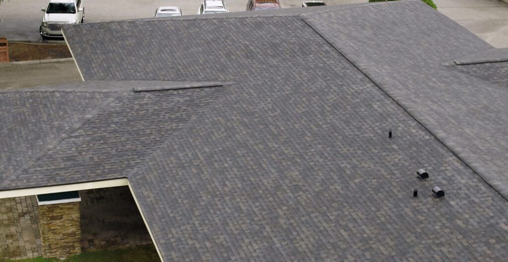 Aerial view of a large building’s roof with dark gray asphalt shingles,