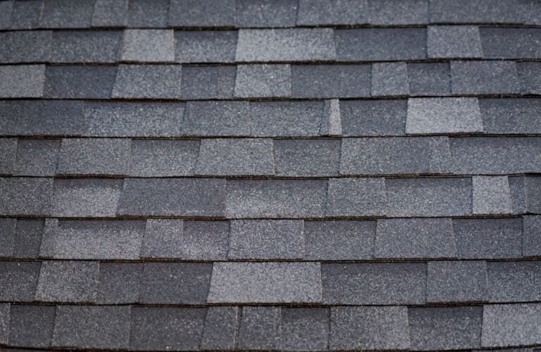 Close-up view of overlapping gray asphalt shingles, showcasing their textured, granular surface and rectangular pattern—features often seen in popular roofs and versatile roof design styles like the Gambrel Roof.