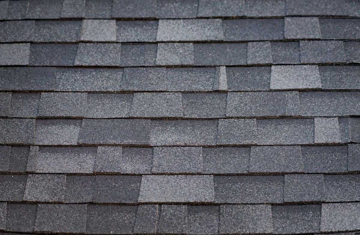 Close-up view of overlapping gray asphalt shingles, showcasing their textured, granular surface and rectangular pattern—features often seen in popular roofs and versatile roof design styles like the Gambrel Roof.