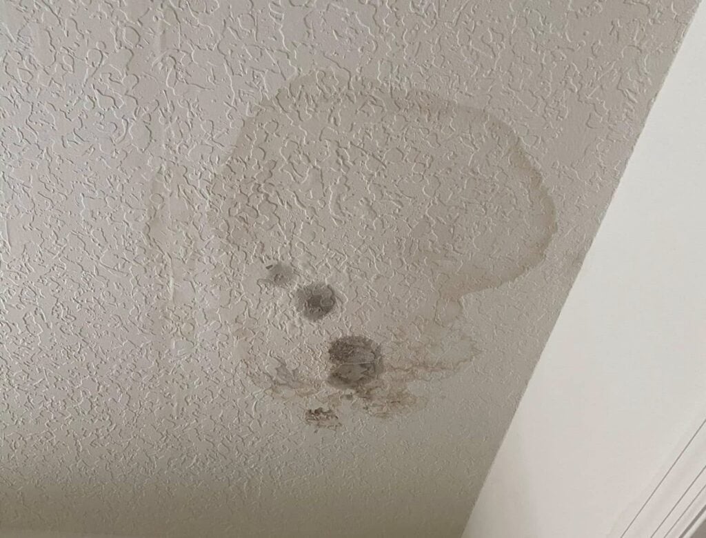 A textured white ceiling with a large, irregular brownish water stain suggests possible water damage above—often seen in homes where roof insurance claims may be needed or homeowner mistakes are made during the claim process.