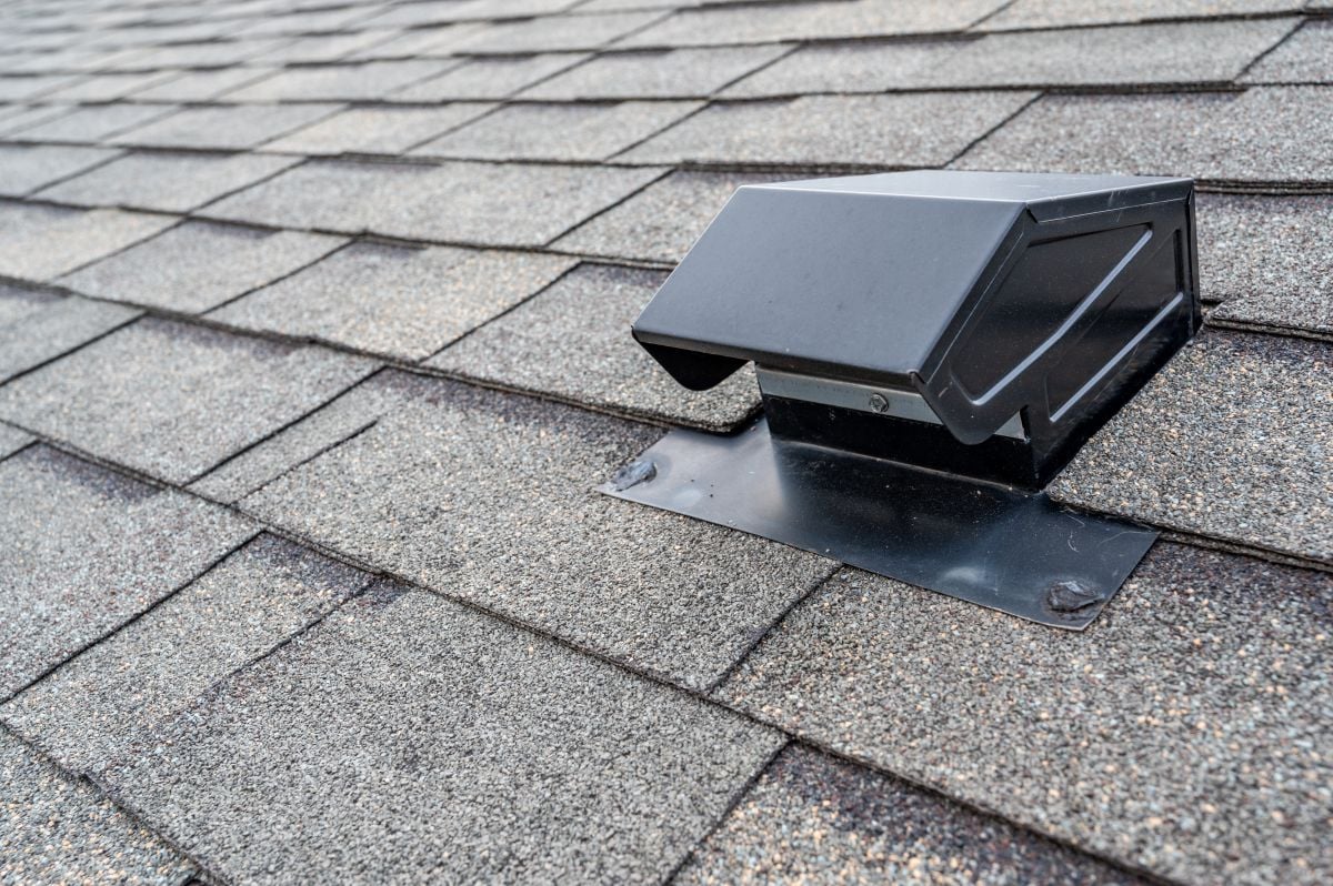 Close-up of a Slant Back Roof Vent installed on gray asphalt shingles, highlighting the detail of the vent, textured roofing material, and the performance benefits it brings to your roof.
