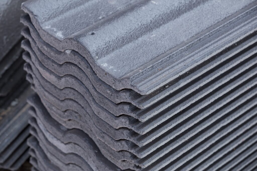Stack of gray corrugated roofing sheets arranged neatly in a pile, showing their wavy texture and layered edges—perfect for use on any roof alongside materials like concrete tile or clay tile.