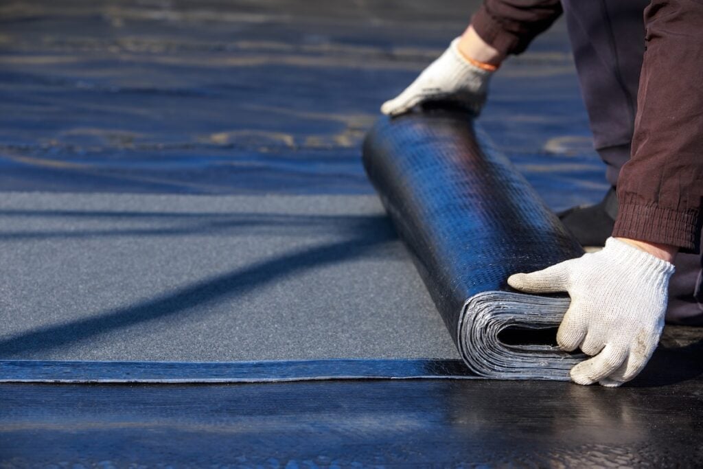The worker puts roofing material in the open air